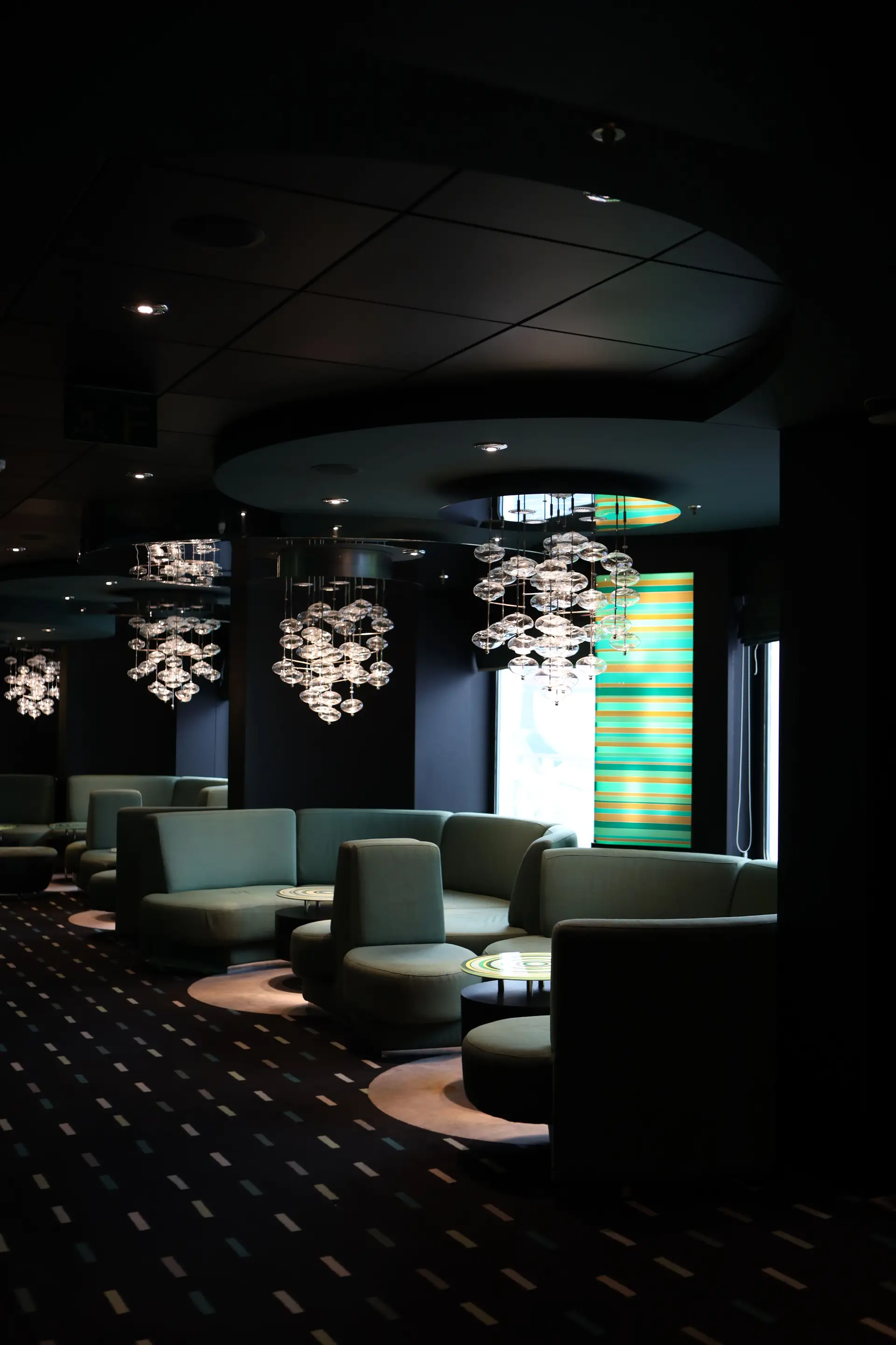 Stemningsfull kveld i Merqaviancrest kasinolounge med varme lysekroner og moderne arkitektur
